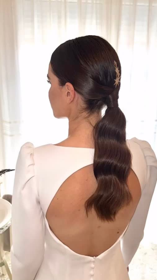Coleta baja de novia con ondas y horquilla dorada